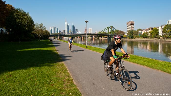 A cyclist rides on the Main Cycle Path with the Frankfurt skyline in the background.