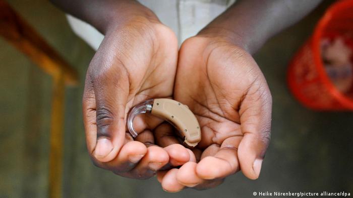 Boy from Africa holds a hearing aid in both hands